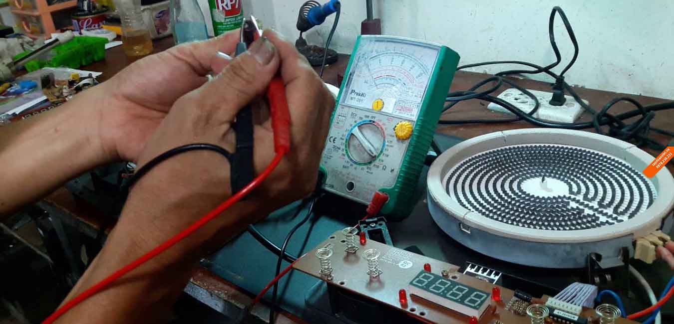 Kỹ thuật viên đang kiểm tra lỗi bo mạch trên bếp từ nội địa Nhật tại nhà khách hàng